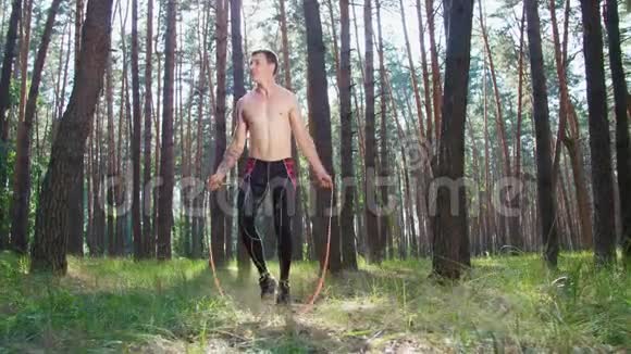 一个年轻的运动员赤裸的躯干跳绳用一根橡皮绳和一根交叉绳做力量练习视频的预览图