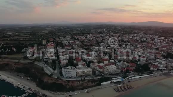 飞越沿海城镇的房屋屋顶日出场景NeaKallikratia希腊视频的预览图