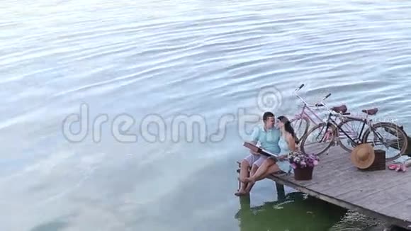 一对年轻夫妇坐在码头上视频的预览图