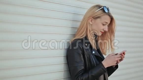 时尚年轻漂亮的女孩手里拿着智能手机女孩在看手机屏幕反对视频的预览图