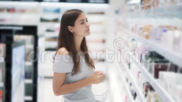 年轻的女人在化妆品店里选择香水闻一闻慢动作视频的预览图