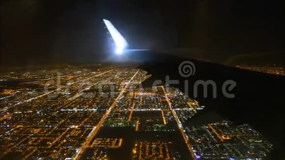 深黑天空下大城市灯光照射下乘用飞机机翼的可观空中飞行景观视频的预览图