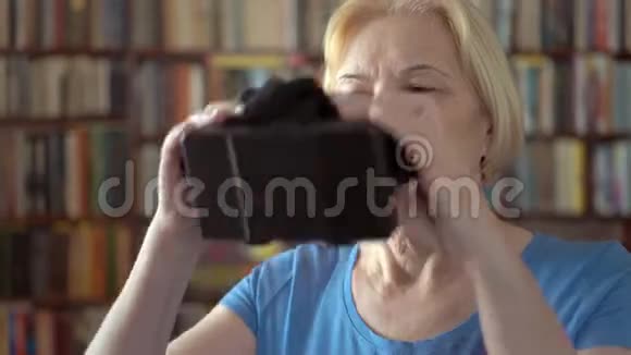 现代高级女性在家使用虚拟现实眼镜背景书架视频的预览图
