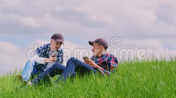 两个十几岁的男孩在大自然中休息使用智能手机视频的预览图