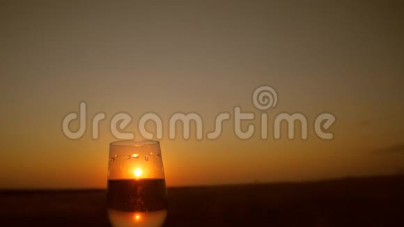 在美丽的夕阳背景下手捧一杯葡萄酒的剪影视频的预览图