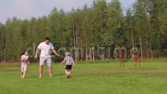 爸爸儿子和女儿夏天在绿茵场上踢足球踢足球视频的预览图