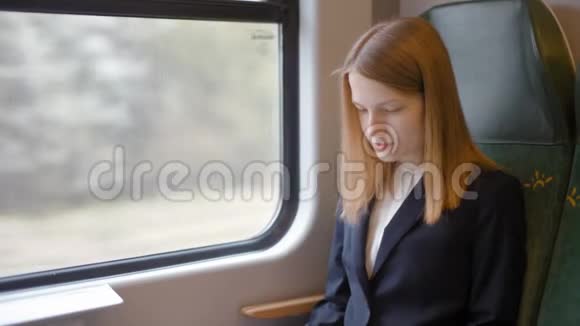 一位年轻的商务女士正在火车上使用她的笔记本电脑和手机视频的预览图