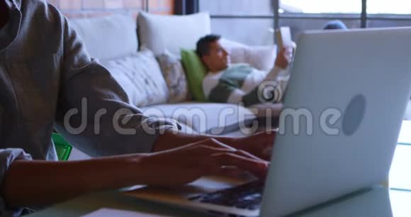 女人用笔记本电脑男人在沙发上看书视频的预览图