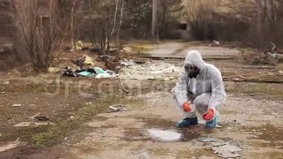 穿着生物危险服和防毒面具的人拿着水和地面进行分析视频的预览图