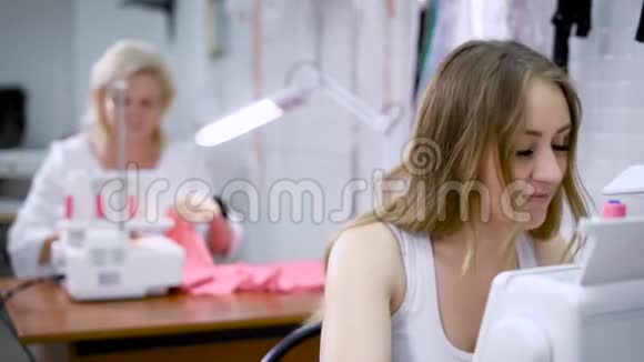 快乐迷人的年轻女裁缝坐在缝纫机上缝制视频的预览图