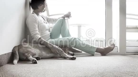 悲伤的女人坐在靠近友好狗的地板上视频的预览图