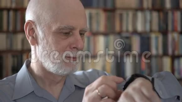 现代老人在家使用智能手表口述信息背景书架视频的预览图