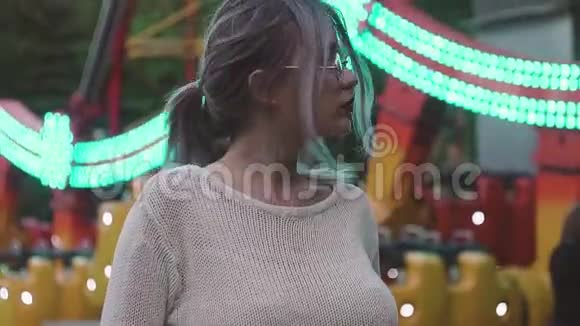 戴眼镜的漂亮女孩站在游乐园的秋千附近视频的预览图