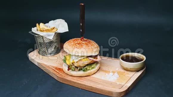 热汉堡和炸薯条和红酱都在黑板上用刀子刺穿并准备以4k分辨率食用视频的预览图