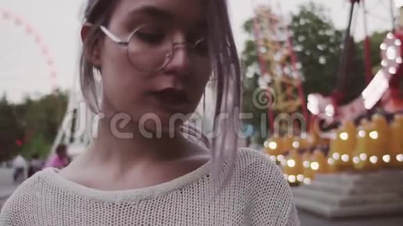 戴眼镜的悲伤少女站在游乐园的秋千附近视频的预览图