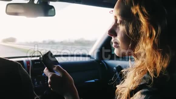 一个年轻的女人坐在副驾驶座上手里拿着手机去汽车旅行很好视频的预览图