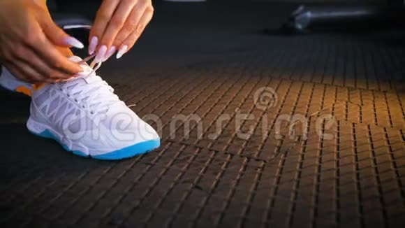合适的女人坐在健身房的地板上系鞋带运动鞋视频的预览图