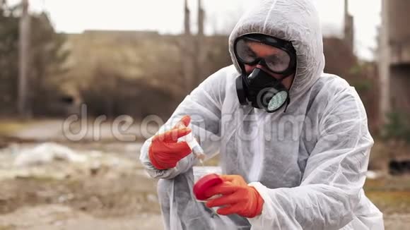 穿着生物危险服和防毒面具的人拿着水和地面进行分析视频的预览图