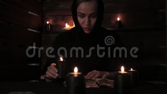 美丽的修女拿着蜡烛读着那本突出火焰的旧书基督教概念视频的预览图