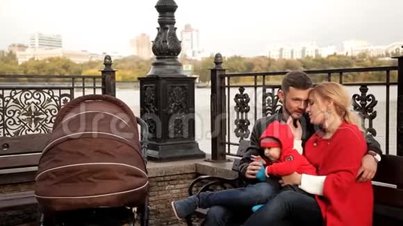 幸福的一家人正坐在水边的长凳上视频的预览图