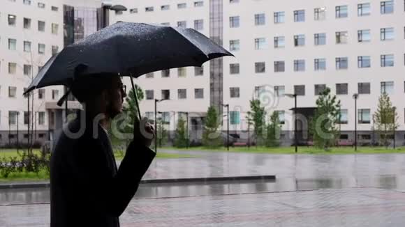 一位严肃的经理穿着经典的西装穿着一件外套手里拿着雨伞下雨时去了他的办公室视频的预览图
