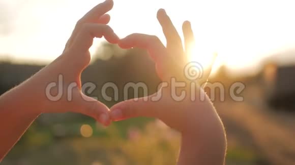 女孩做心手逆天孩子手形成一个心形与日落剪影爱梦夏天视频的预览图