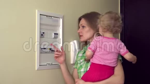 女人带着婴儿在手臂检查断路器电器回家4K视频的预览图