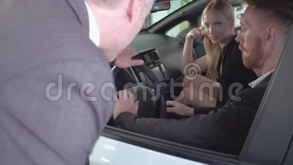 幸福夫妇坐在新车里检查它汽车经销商向买家展示汽车视频的预览图