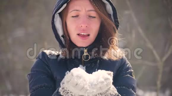 快乐的年轻女人在美丽的冬日玩得开心享受新鲜的雪戴着温暖手套的女孩吹雪户外活动视频的预览图