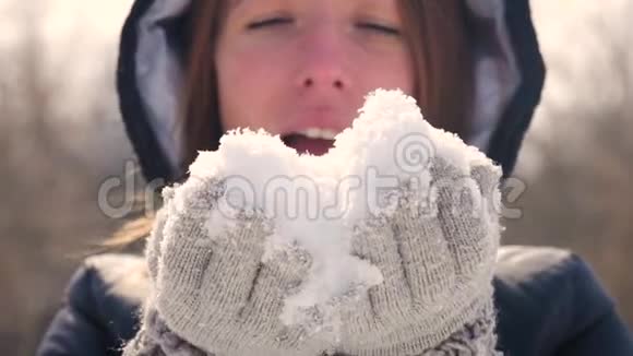 快乐的年轻女人在美丽的冬日玩得开心享受新鲜的雪戴着温暖手套的女孩吹雪户外活动视频的预览图