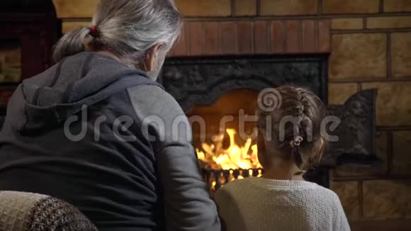 祖父带着孙女看着壁炉里的火焰视频的预览图