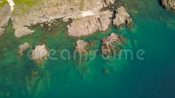 海水中的蓝色泻湖和海岸上的岩石悬崖空中景观来自飞行无人机空中射击海洋和山地视频的预览图