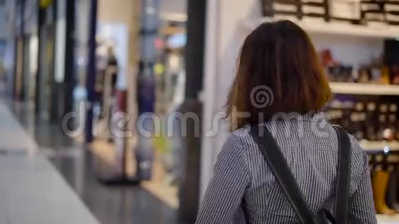 一个年轻漂亮的小女孩走过一个巨大的商场穿过商店的窗户4这个女孩正在寻找合适的人选视频的预览图