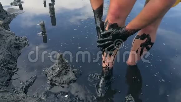 年轻人用黑色医用泥浆在咸水湖做健康的皮肤面膜高清慢速运动视频的预览图