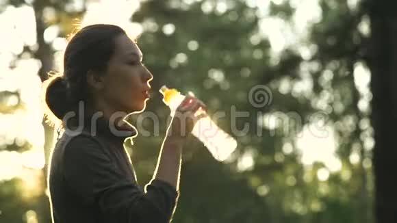 一个夏天漂亮的年轻女人在公园里运动时喝水视频的预览图