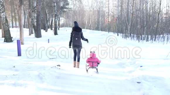 妈妈把她的孩子卷在雪橇上视频的预览图