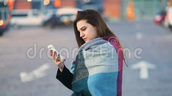 在春天的城市街道上一个棕色头发的漂亮女孩敲着手机屏幕稳定凸轮慢镜头视频的预览图