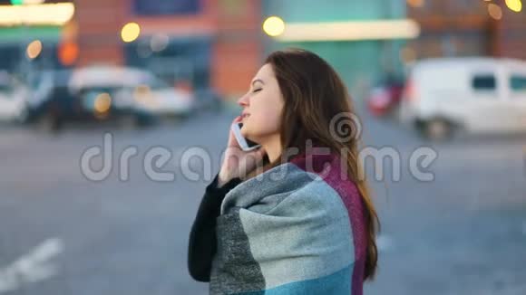 年轻漂亮的商务女孩肩膀上有一块地毯在城市街道上打电话稳定凸轮缓慢移动视频的预览图