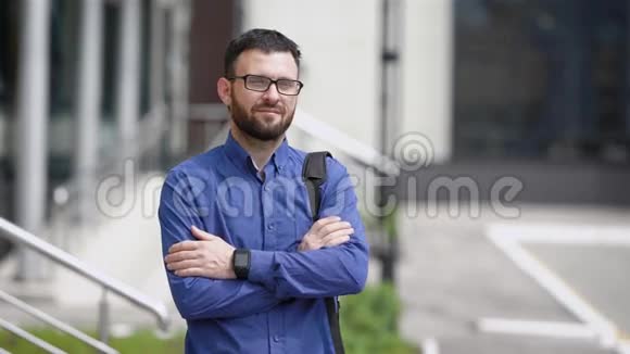 一个蓄着络腮胡子黑发的人看上去像个商人站在公司大楼附近视频的预览图