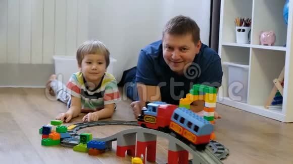 家庭观念男孩和爸爸在木地板上玩火车父亲与儿子视频的预览图