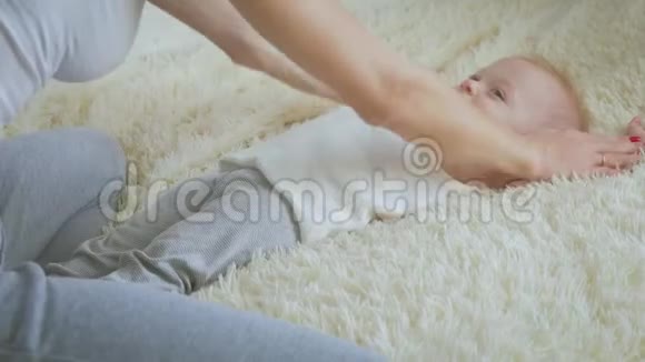 妈妈在家里在床上给小儿子按摩加强婴儿运动家庭保健概念视频的预览图