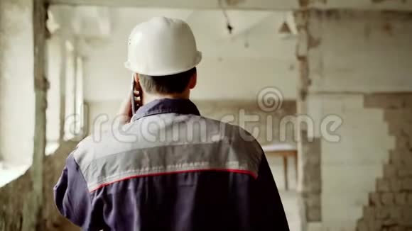 一个成年的男工程师用他的手机说话沿着工地走到图纸那里有一个视频的预览图