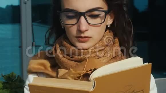 戴眼镜的年轻迷人女孩在看书视频的预览图