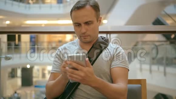 年轻人坐在购物中心的咖啡馆里用智能手机浏览阅读新闻聊天朋友视频的预览图
