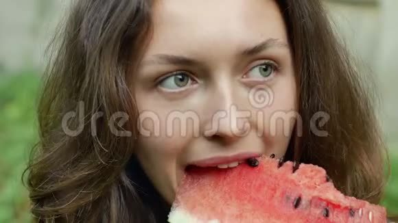 美丽的年轻女子正高兴地吃着西瓜看着镜头视频的预览图