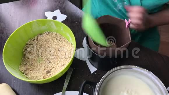 女人把面包屑加到模子里做一个饼干面包屑和牛奶果冻蛋糕视频的预览图