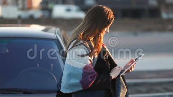 可疑的女孩带着围巾在街上按摩药片靠在车上慢稳定视频的预览图