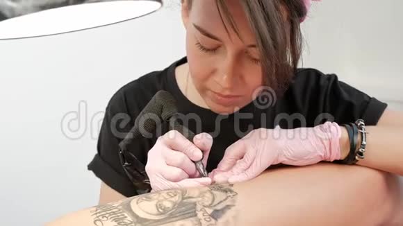 纹身大师迷人的女人与可怕的纹身客户的女孩在臀部黑色纹身机和墨水视频的预览图