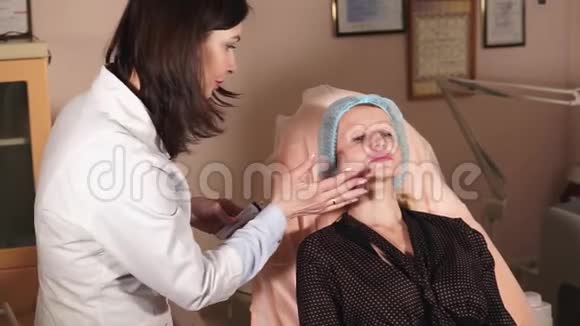 整形外科医生轻轻地在病人脸上涂药膏麻醉视频的预览图