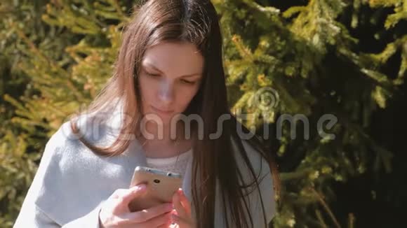 一幅美丽的黑发美女在公园的手机里读留言的肖像视频的预览图